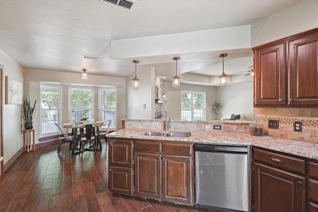 kitchen with light stone counters, stainless steel dishwasher, dark hardwood / wood-style floors, pendant lighting, and sink