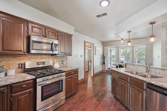 kitchen with decorative light fixtures, dark hardwood / wood-style flooring, sink, appliances with stainless steel finishes, and backsplash