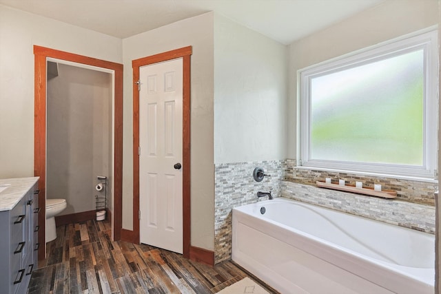 bathroom featuring vanity, a washtub, hardwood / wood-style flooring, and toilet