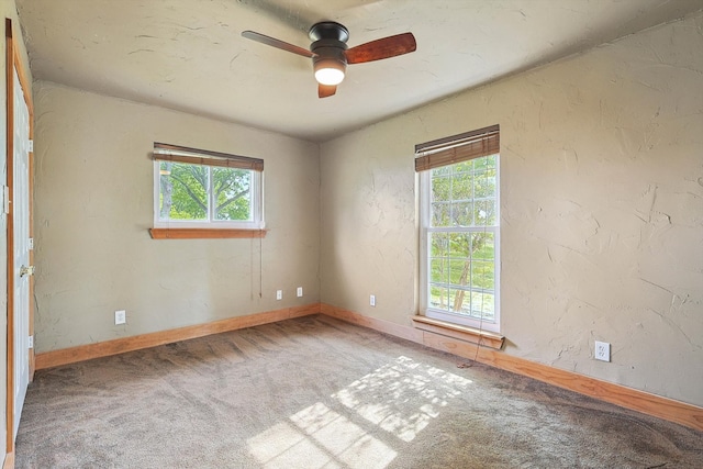 carpeted empty room featuring ceiling fan and plenty of natural light