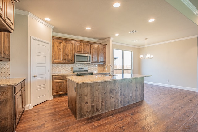 kitchen featuring appliances with stainless steel finishes, an island with sink, dark hardwood / wood-style floors, backsplash, and sink