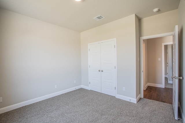 unfurnished bedroom featuring a closet and dark colored carpet