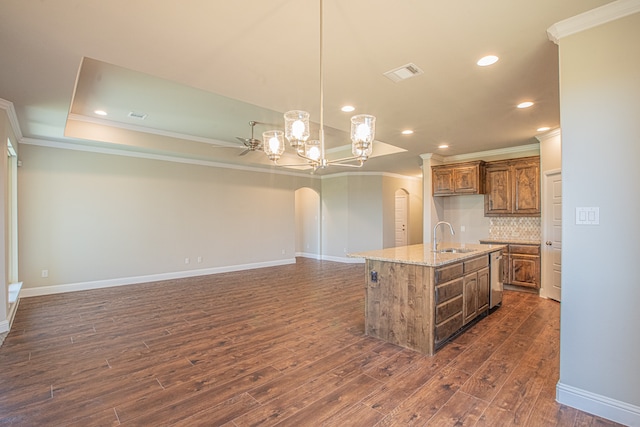 kitchen featuring light stone counters, dark hardwood / wood-style floors, tasteful backsplash, an island with sink, and pendant lighting