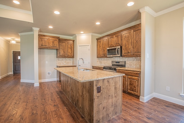 kitchen featuring dark hardwood / wood-style floors, stainless steel appliances, a center island with sink, and backsplash