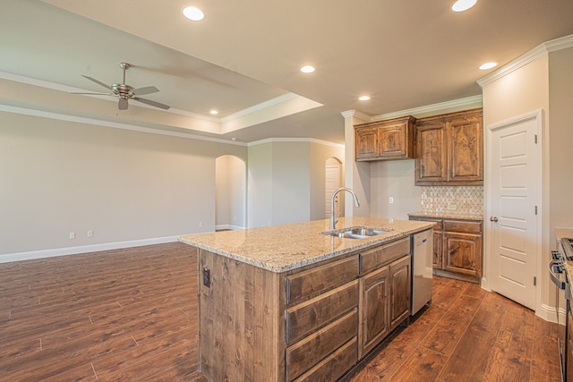 kitchen with a center island with sink, a raised ceiling, ornamental molding, dark wood-type flooring, and sink