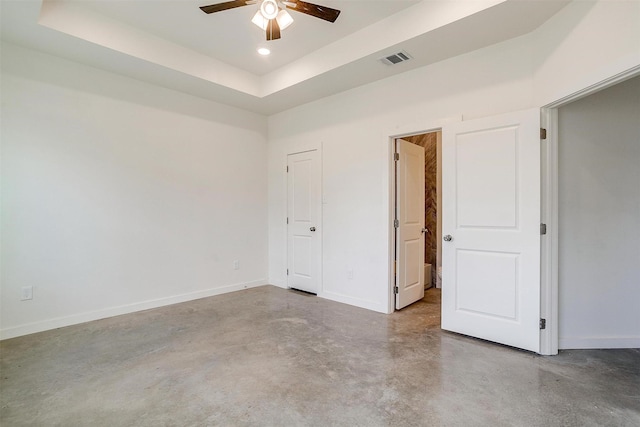 unfurnished bedroom featuring ceiling fan, concrete floors, and a raised ceiling