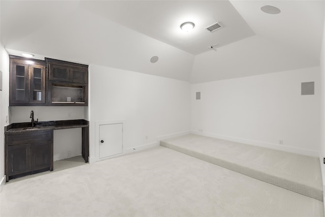 carpeted empty room with vaulted ceiling and sink