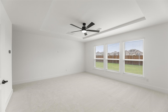 carpeted spare room with ceiling fan and a raised ceiling