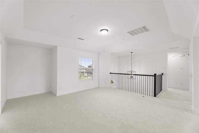 carpeted empty room with an inviting chandelier