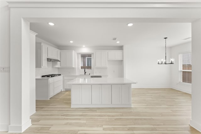 kitchen featuring white cabinets, a center island, light wood-type flooring, and stainless steel gas stovetop