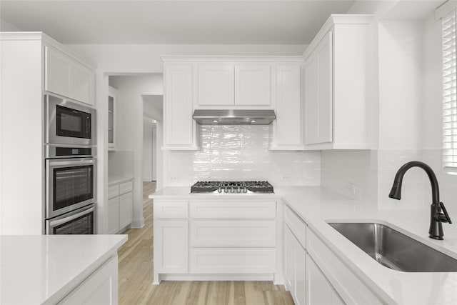 kitchen featuring backsplash, sink, stainless steel appliances, and white cabinets