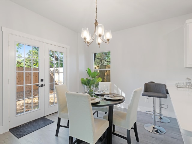 dining area with french doors, light hardwood / wood-style floors, and a notable chandelier