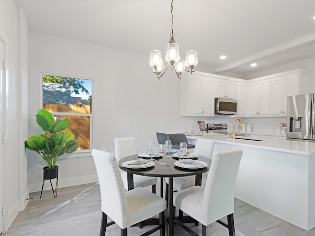 dining room with an inviting chandelier, sink, and light hardwood / wood-style flooring