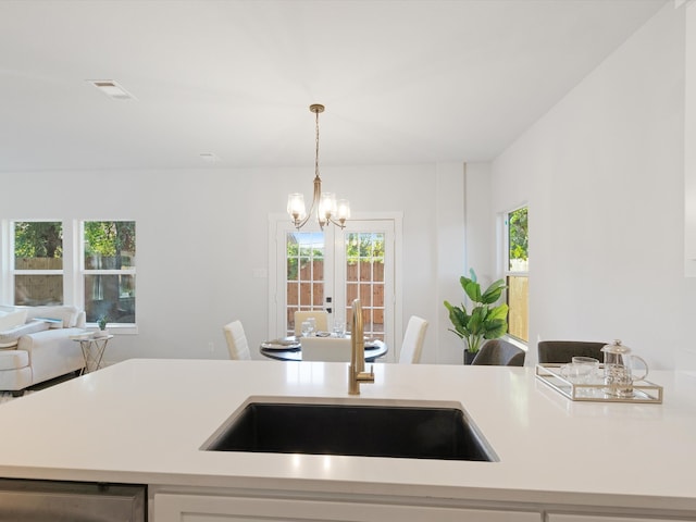 kitchen featuring sink, pendant lighting, french doors, and a notable chandelier