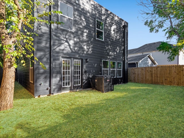 rear view of property with central AC unit and a yard