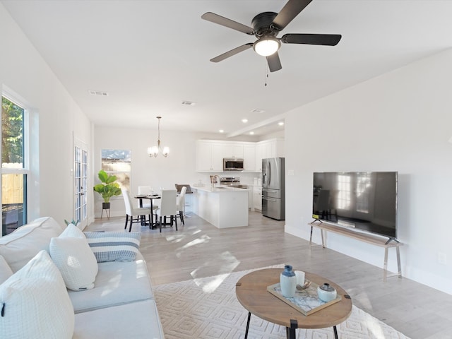 living room featuring light hardwood / wood-style flooring and ceiling fan with notable chandelier