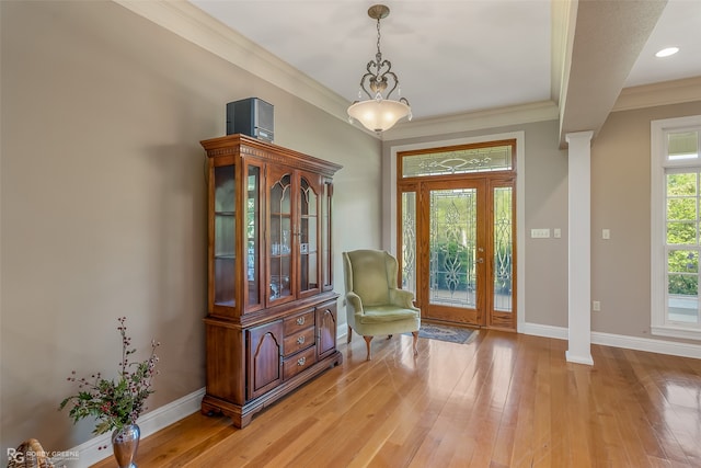 unfurnished room with crown molding, ornate columns, and light wood-type flooring