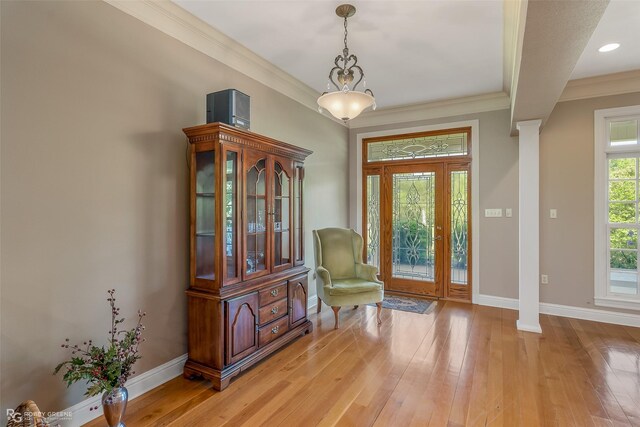 dining room featuring light hardwood / wood-style flooring, decorative columns, an inviting chandelier, and ornamental molding