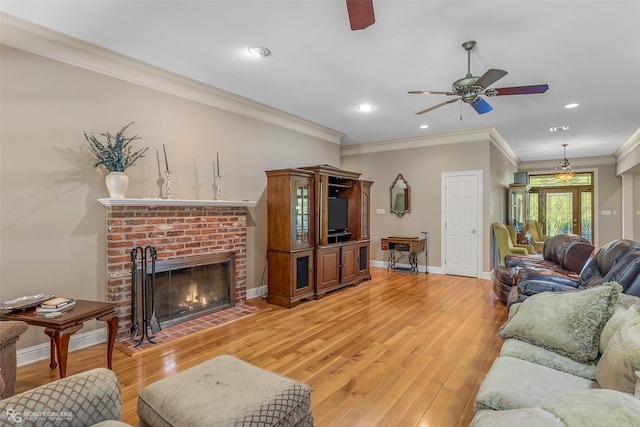 living room with a fireplace, ceiling fan, light hardwood / wood-style floors, and crown molding