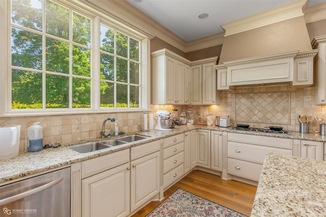 kitchen with light wood-type flooring, backsplash, ornamental molding, stainless steel appliances, and sink