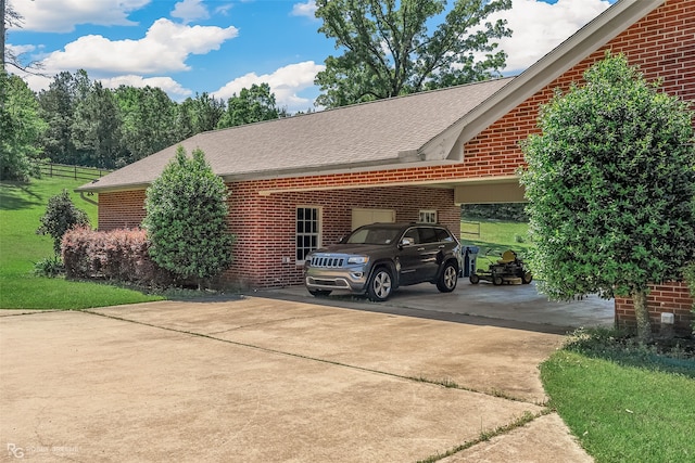 view of side of property featuring concrete driveway, brick siding, and roof with shingles