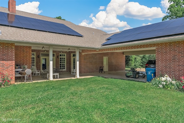 back of property featuring solar panels, ceiling fan, a patio area, and a lawn