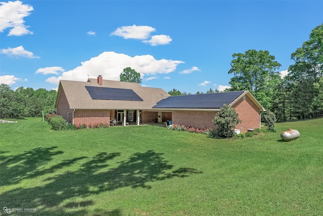 ranch-style home with a front yard and solar panels