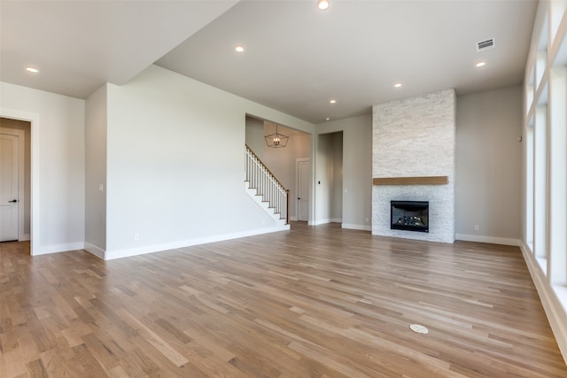 unfurnished living room featuring light hardwood / wood-style floors and a stone fireplace