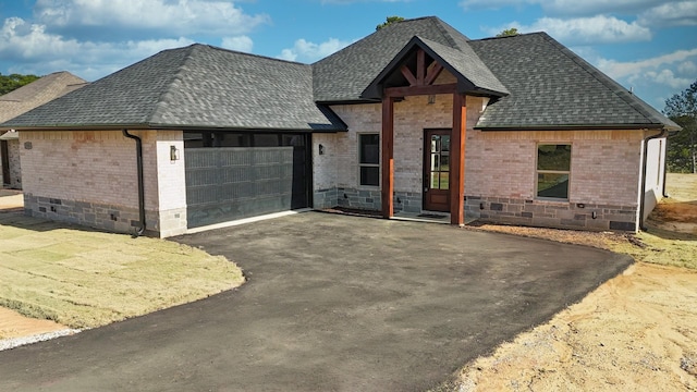 view of front of property featuring brick siding, driveway, a garage, and roof with shingles