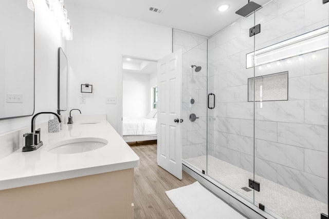 ensuite bathroom featuring recessed lighting, a sink, a shower stall, and wood finished floors