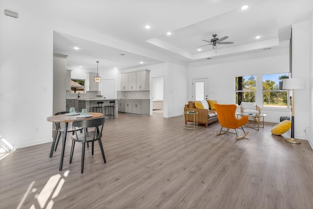 living room featuring baseboards, recessed lighting, and a tray ceiling