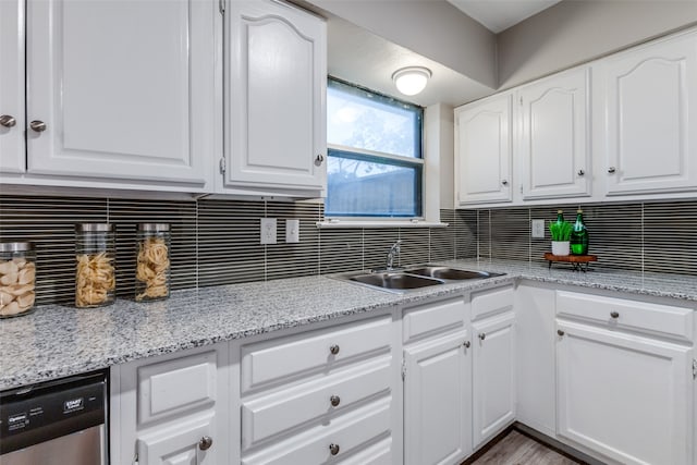 kitchen featuring backsplash, light stone counters, white cabinets, sink, and stainless steel dishwasher