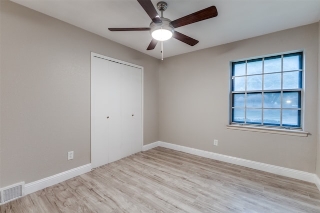 unfurnished bedroom with light hardwood / wood-style flooring, ceiling fan, and a closet