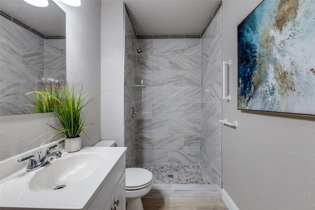 bathroom with toilet, vanity with extensive cabinet space, and a tile shower