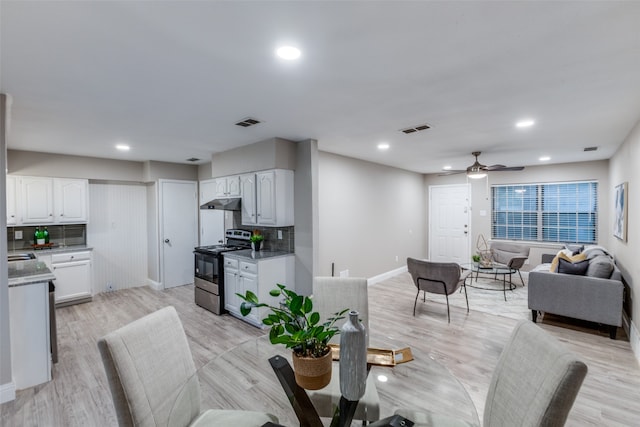 dining room featuring ceiling fan, sink, and light wood-type flooring