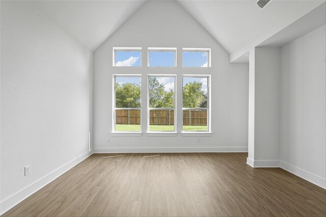 empty room with wood-type flooring and high vaulted ceiling