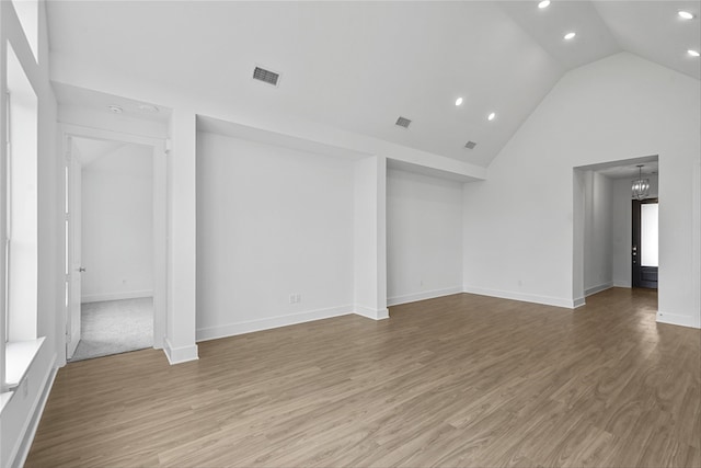 unfurnished room with an inviting chandelier, light hardwood / wood-style flooring, and high vaulted ceiling