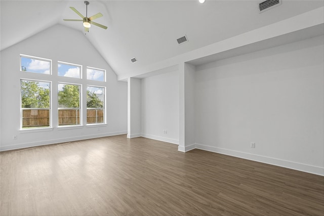 empty room with high vaulted ceiling, dark wood-type flooring, ceiling fan, and a wealth of natural light