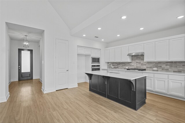 kitchen featuring an island with sink, light wood-type flooring, white cabinets, and appliances with stainless steel finishes