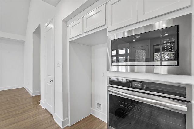 kitchen with white cabinetry, appliances with stainless steel finishes, and dark wood-type flooring