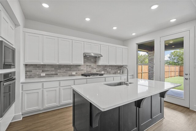 kitchen with stainless steel appliances, white cabinetry, a center island with sink, and sink