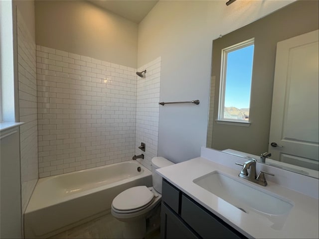 full bathroom featuring vanity, tiled shower / bath, and toilet