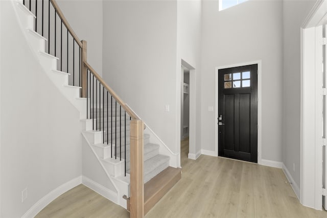 entryway featuring a high ceiling, a healthy amount of sunlight, and light hardwood / wood-style flooring