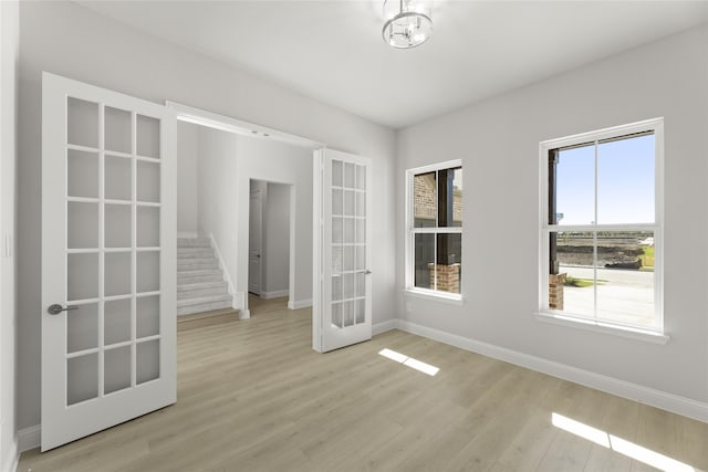 unfurnished room featuring a healthy amount of sunlight, light wood-type flooring, and french doors