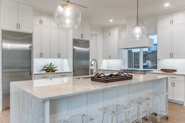 kitchen featuring a center island with sink, appliances with stainless steel finishes, pendant lighting, and white cabinets