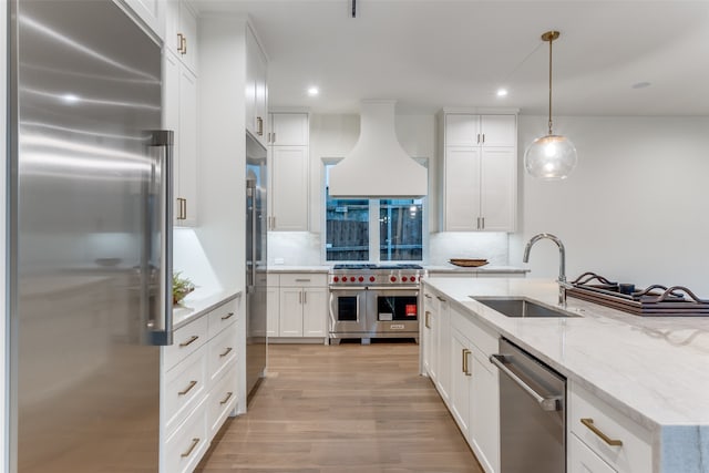 kitchen featuring tasteful backsplash, high quality appliances, hanging light fixtures, white cabinetry, and custom exhaust hood