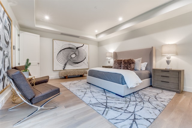 bedroom featuring light hardwood / wood-style flooring and a tray ceiling