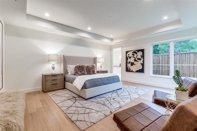 bedroom featuring a raised ceiling and light hardwood / wood-style flooring