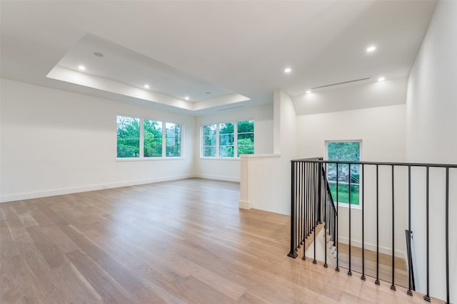 unfurnished room featuring a tray ceiling and light hardwood / wood-style floors