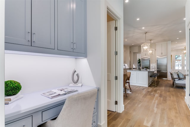 home office featuring a notable chandelier and light hardwood / wood-style flooring